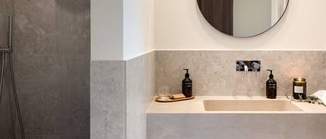A modern bathroom with a shower, a sink, and a mirror.