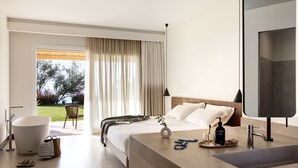Habitación de hotel moderna con una cama grande, un baño con un espejo amplio y vistas al exterior.