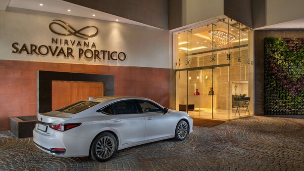 Un coche blanco estacionado frente a un edificio con un letrero que dice 'Nirvana Sarovar Portico'.
