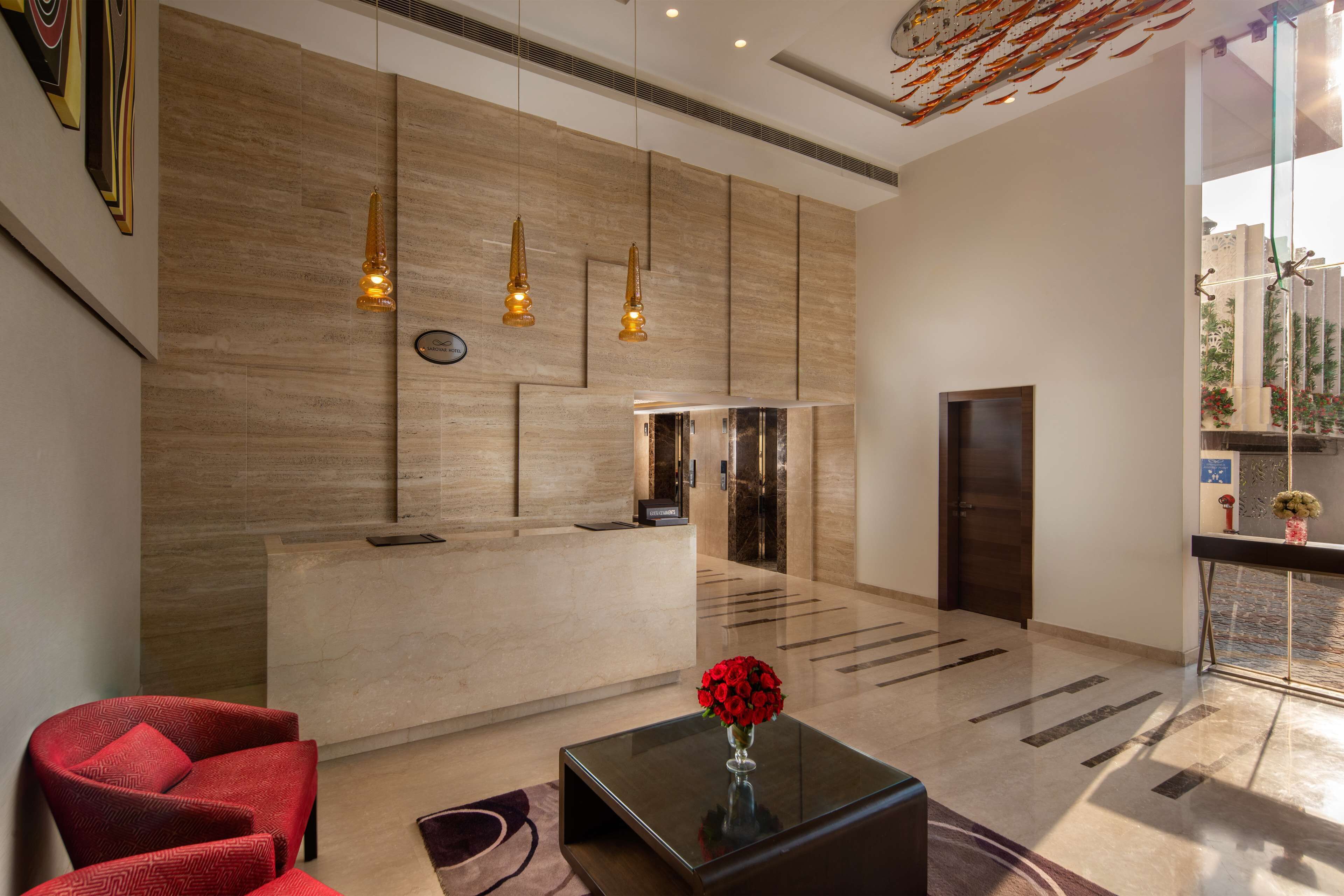 A modern hotel lobby with a reception desk, seating area, and a large window offering a view of the outdoors.
