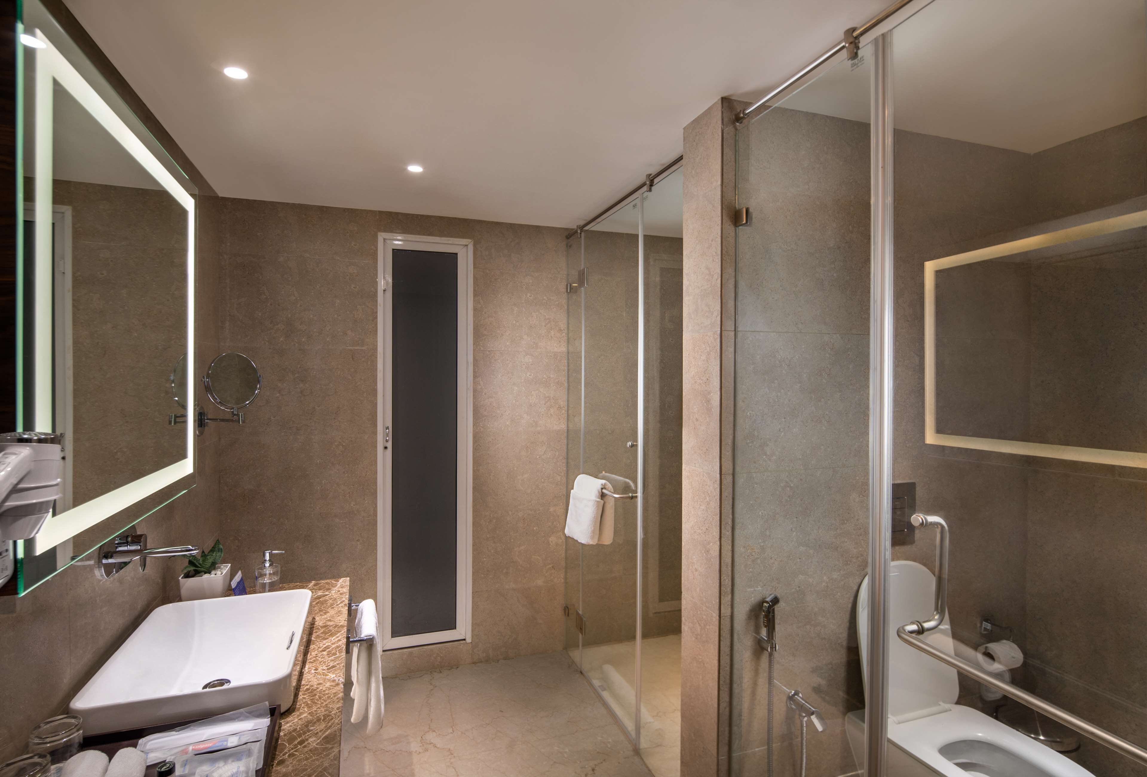 A modern bathroom with a glass-enclosed shower, a sink, and a toilet.