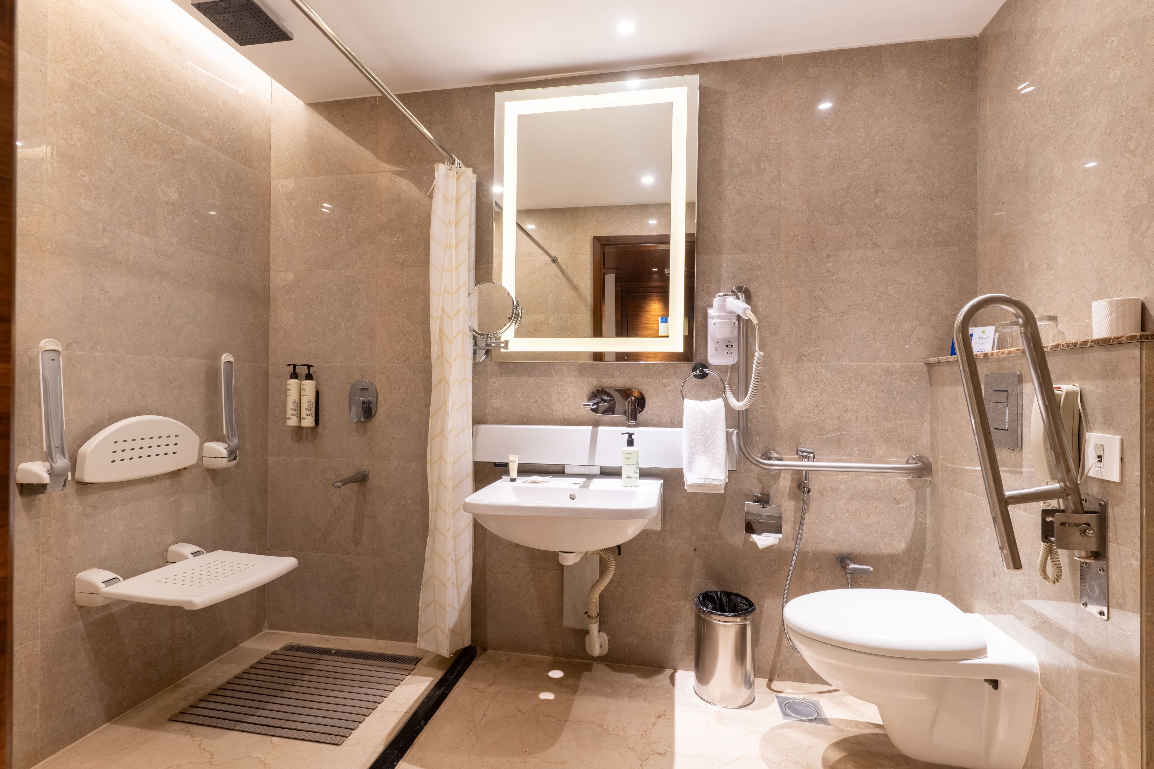 Un baño moderno con ducha, lavamanos, inodoro y espejo.