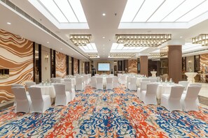 A conference room with round tables, white chairs, and a large screen. - Nirvana Sarovar Portico Gorakhpur (Gorakhpur)