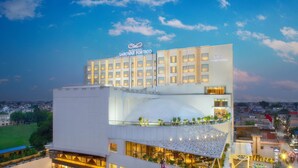 Un hotel moderno con un letrero llamativo, varios pisos y una terraza en la azotea.