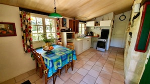 Une cuisine compacte comprenant une table à manger, des chaises, un four à micro-ondes, un évier et une cuisinière.