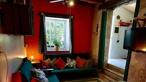 Un salon confortable avec un canapé, une table basse, un téléviseur et un ventilateur de plafond.