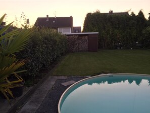 Un cortile residenziale con piscina, prato curato e muro in pietra.