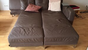 A brown sofa with two pillows, a laptop, and a power strip on a wooden floor. - Apartment in Haltern am See (Haltern am See)