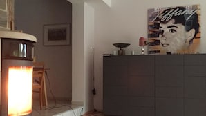 A modern living room with a fireplace, a large dark-colored cabinet, and a wall-mounted Tiffany lamp. - Apartment in Haltern am See (Haltern am See)