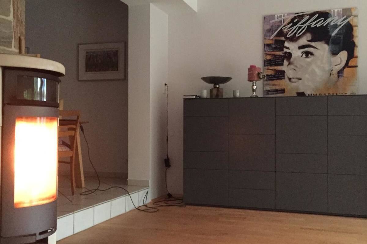 Un salon moderne avec une cheminée, un grand meuble de couleur sombre et une lampe Tiffany fixée au mur.
