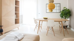 A modern, well-lit room with a wooden cabinet, a dining table with chairs, and a hanging pendant light.