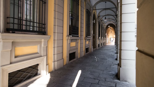 A corridor with arched ceilings and a tiled floor, leading to a distant open area.