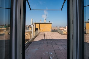 A rooftop terrace with a yellow building, railings, and a clear sky. - Appartamento Galliera (Bologna)