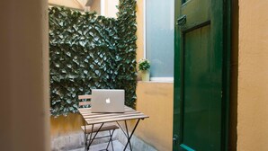 A small outdoor area with a table, a laptop, and a door. - Appartamento Santa Margherita (Bologna)