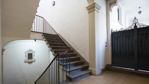 A staircase with a handrail, a white wall with a framed picture, and a black gate. - Appartamento Santa Margherita (Bologna)