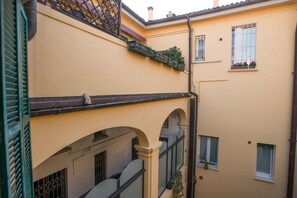 Um edifício com fachada amarela, várias janelas e varandas com plantas.