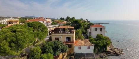 A coastal village with traditional architecture, including terracotta-roofed buildings and a stone staircase leading to a beach.