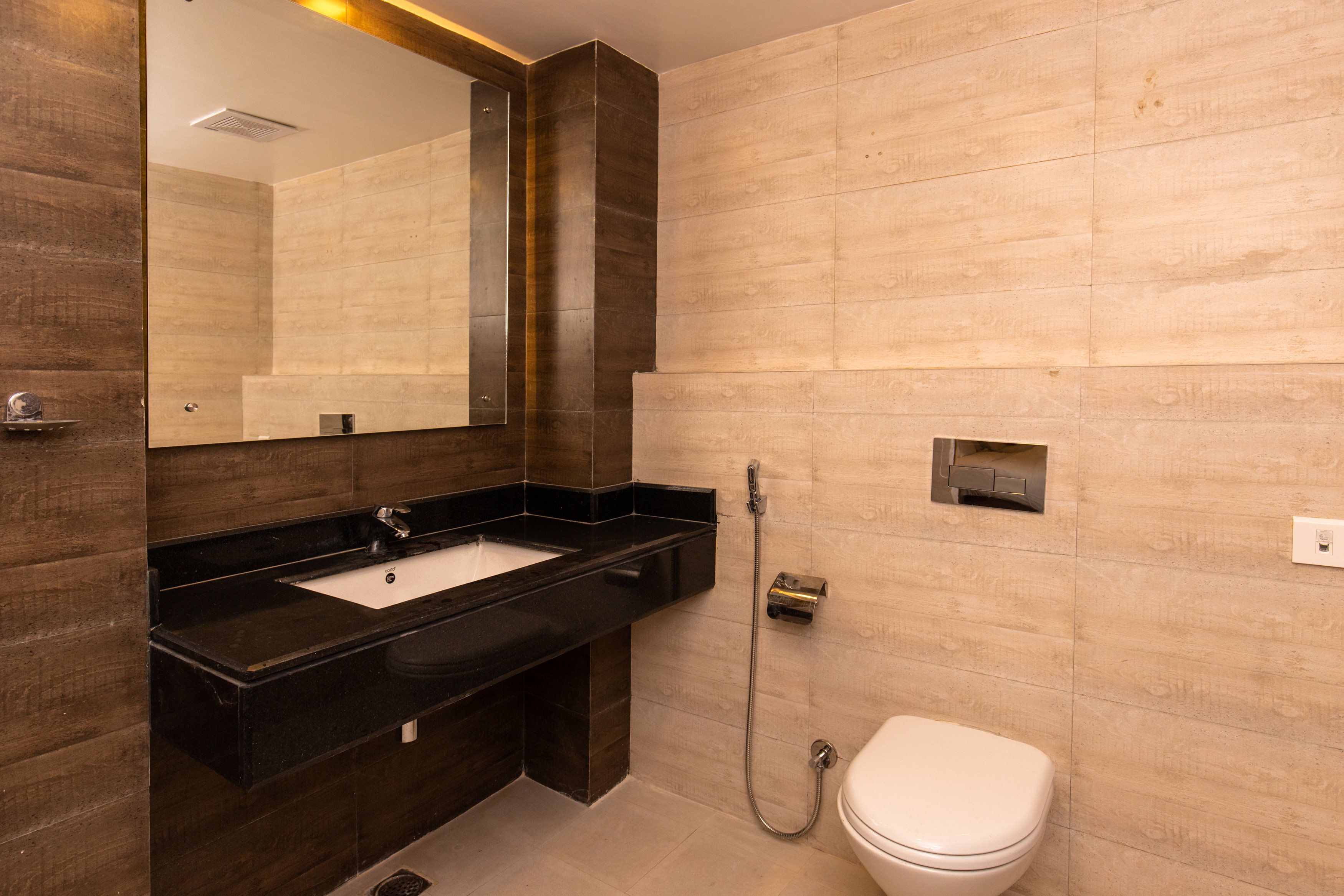 A modern bathroom with a black sink, a mirror, a toilet, and a shower.