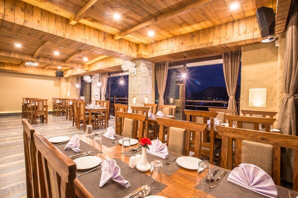 Un restaurante con mesas y sillas de madera, listo para comer.