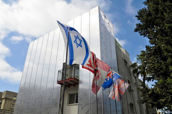 A building with a balcony and flags, including the Israeli flag. - G38 Rental Apartment Building (Haifa)