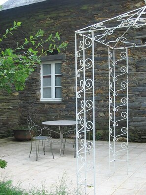 Un edificio de piedra con una ventana y una estructura de pérgola metálica.