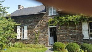 A stone house with a door open, surrounded by greenery. - Chambres d'hotes la Merais (Marsac-sur-Don)