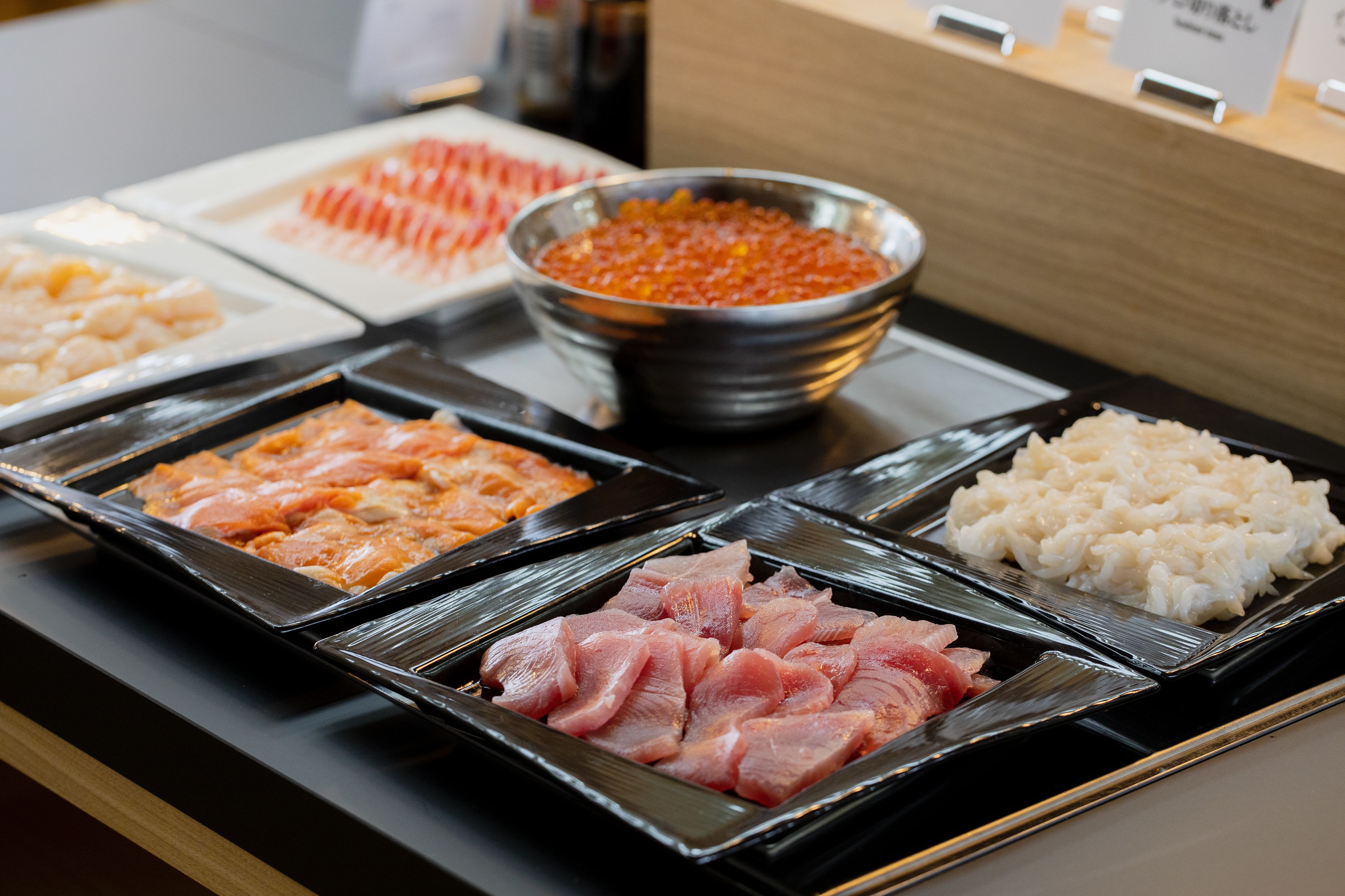 A buffet with various food items including raw fish, rice, and other dishes.