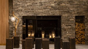 A modern interior with a brick wall, a fireplace, and several dark wooden stools.