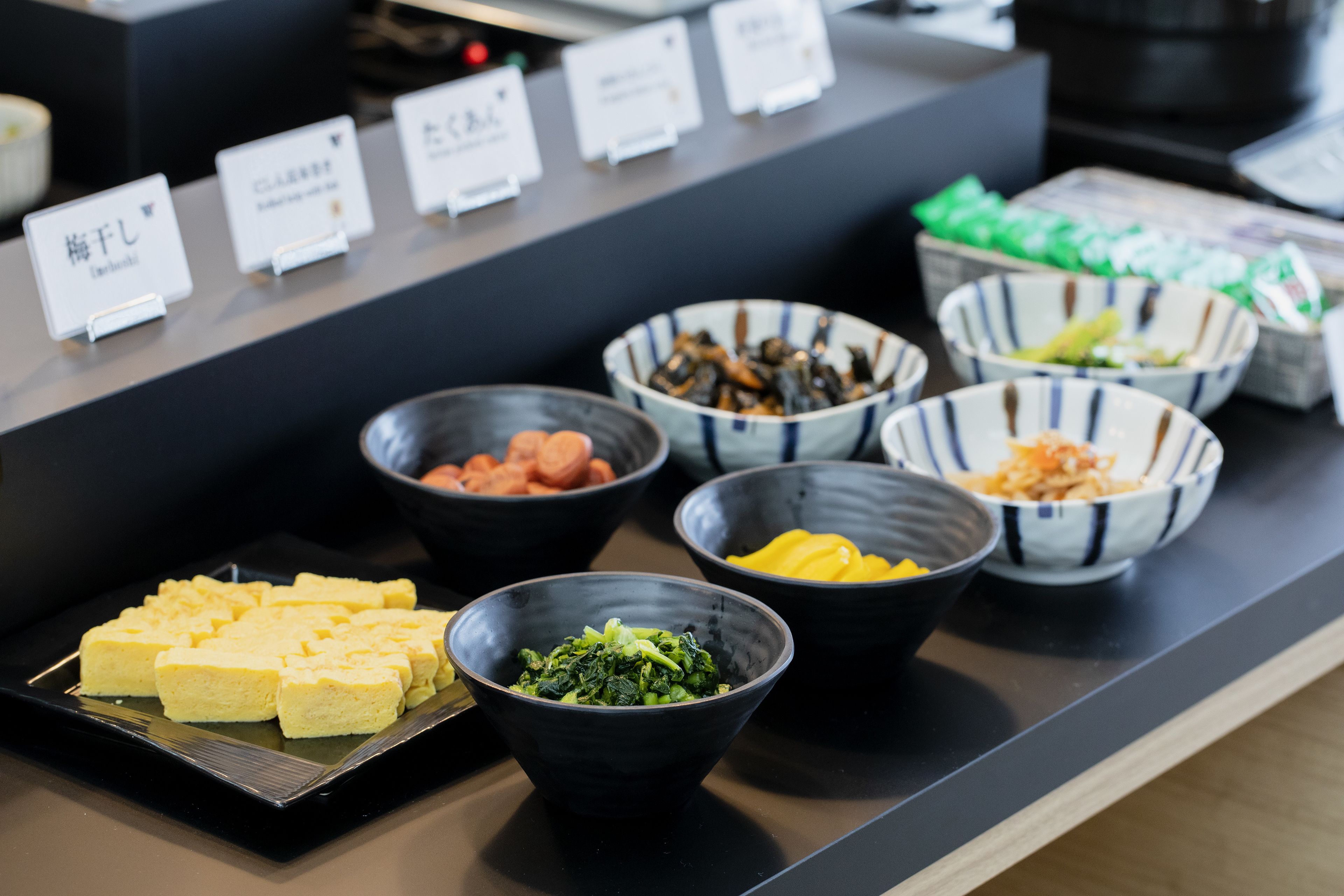 Ein Buffet mit verschiedenen Speisen, darunter Tofu, Gemüse und andere zubereitete Gerichte.