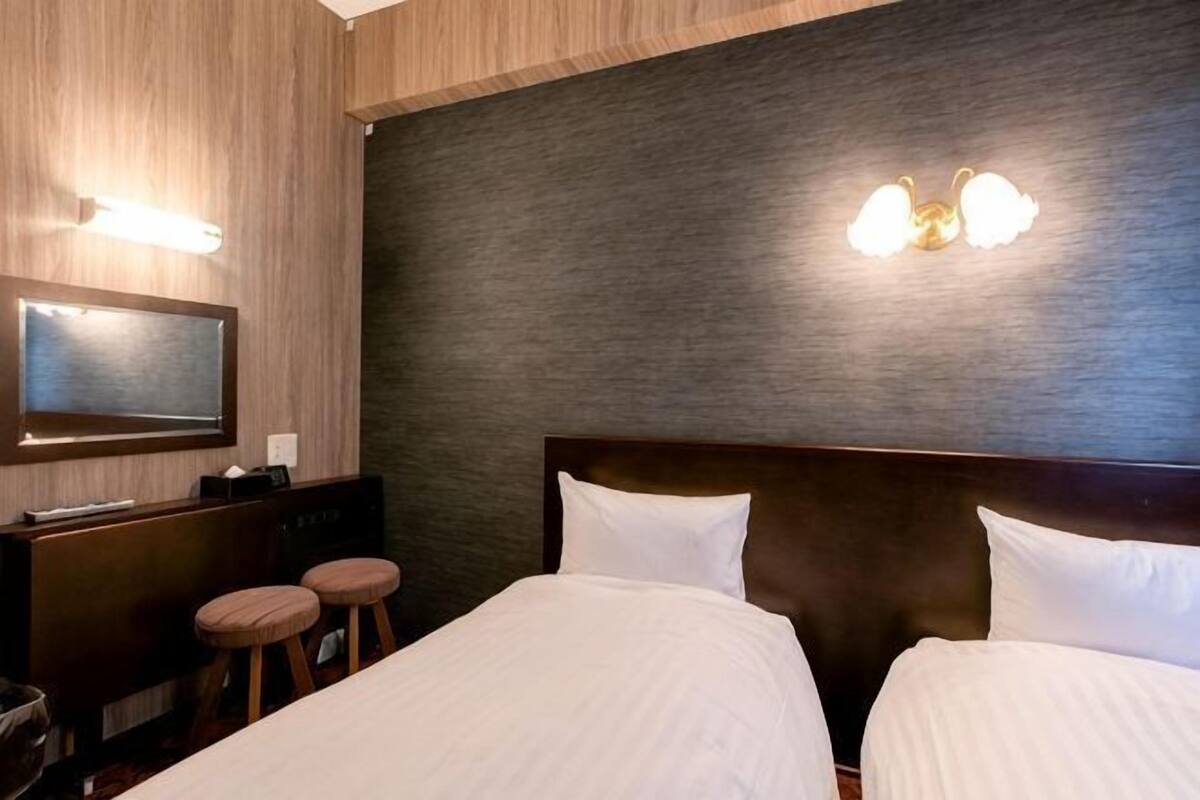 A hotel room with a bed, a desk with a chair, and a television.