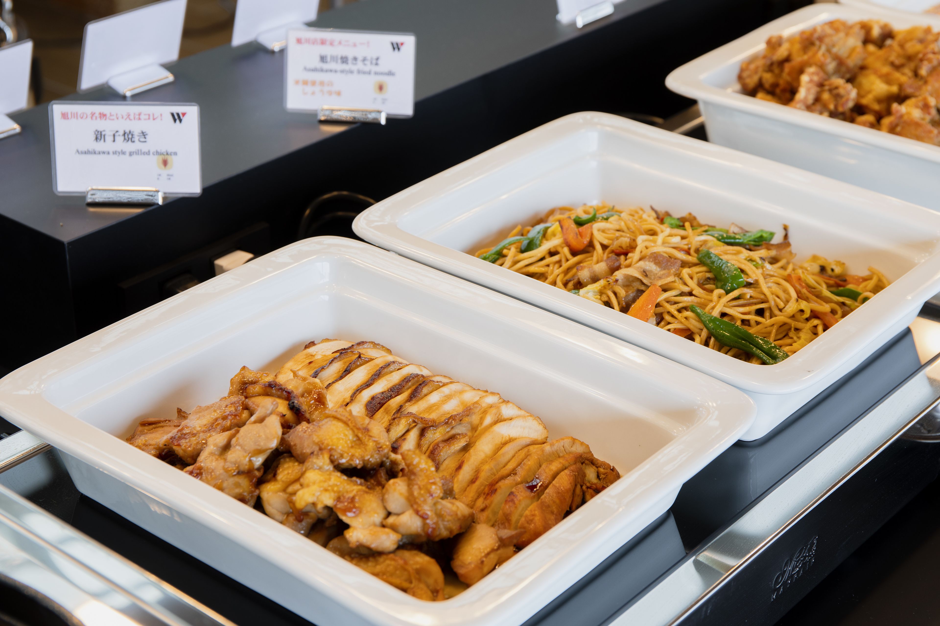 A buffet with various dishes, including grilled chicken and stir-fried vegetables.