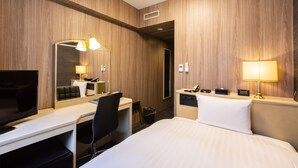 A hotel room with a bed, desk, chair, TV, and lamps.