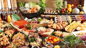 A buffet with various food items, including meats, vegetables, and fruits.