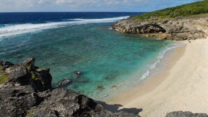 A coastal beach with clear turquoise waters, rocky outcrops, and a sandy shoreline. - Le Recif Guest House (Rodrigues Island)