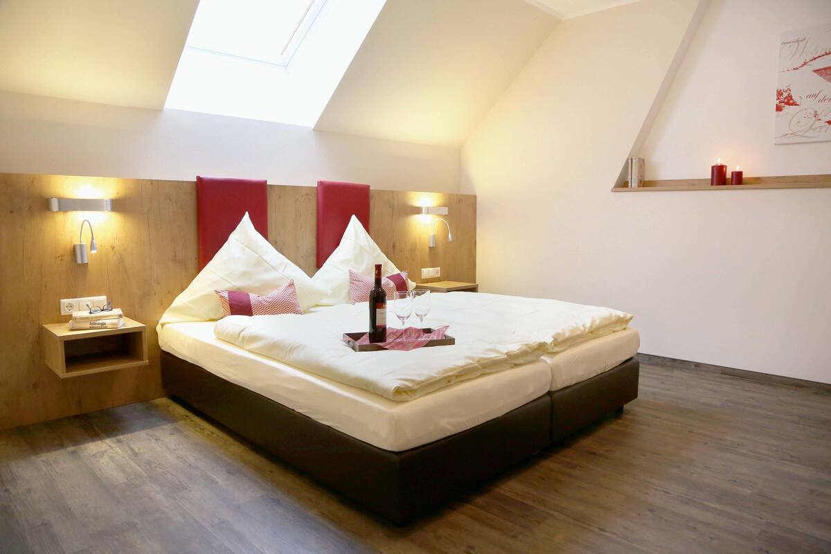 A bedroom with a large bed, wooden headboard, bedside tables, and a skylight.