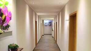 Un pasillo largo y estrecho con suelo de madera, paredes blancas e iluminación empotrada.