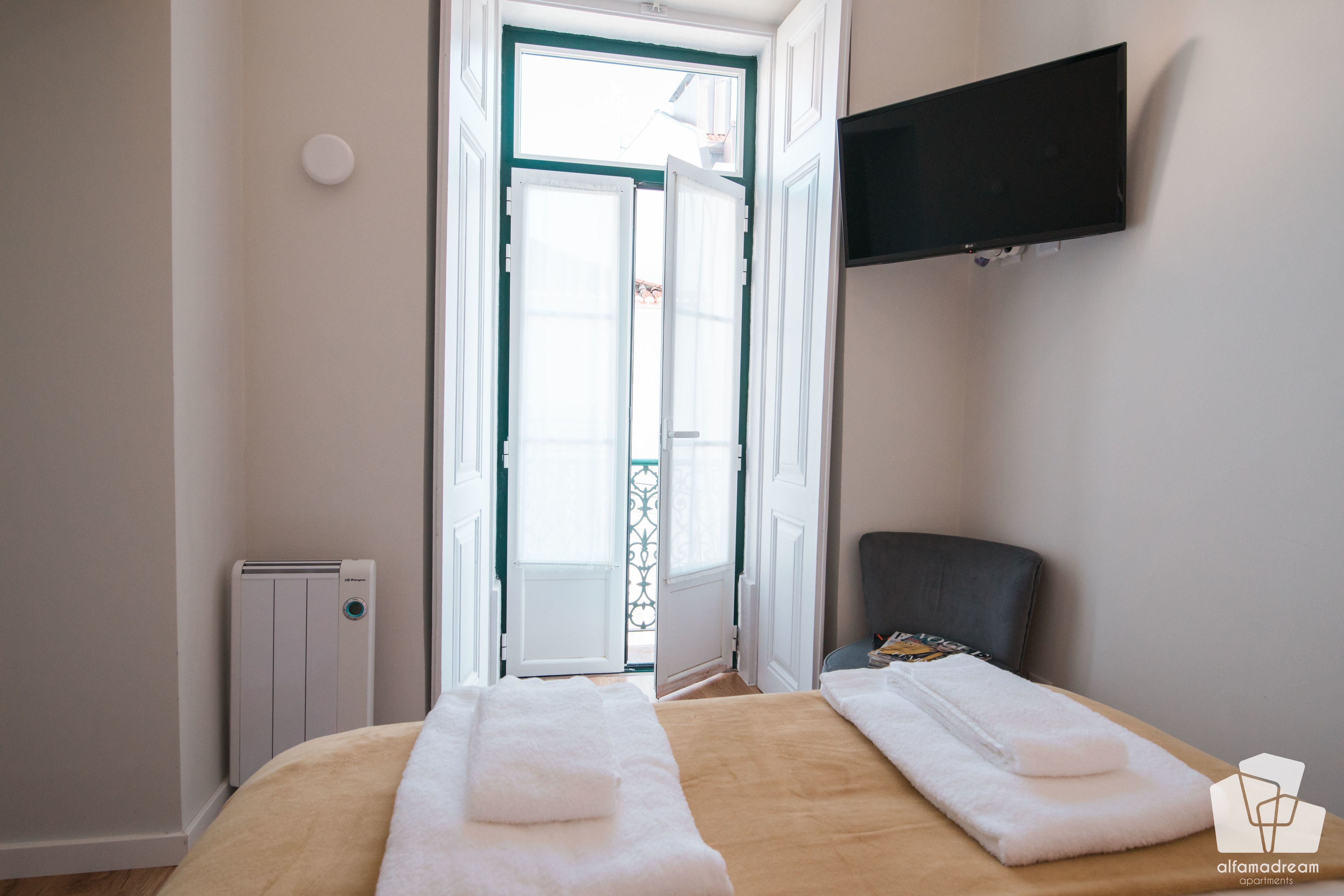 Une chambre d’hôtel avec un lit, un téléviseur fixé au mur et un radiateur.