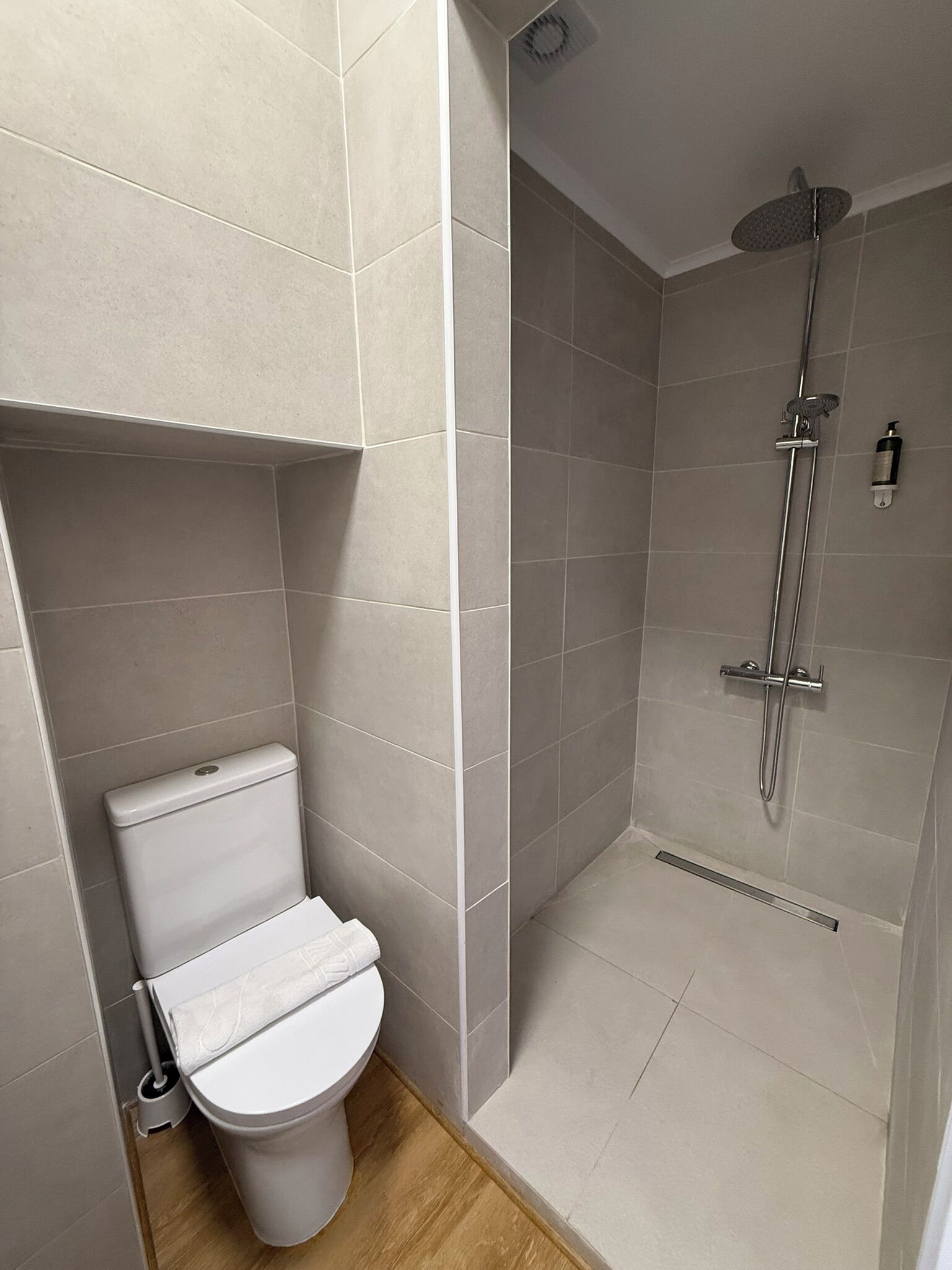 Et moderne badeværelse med toilet, bruser og flisebeklædte vægge.