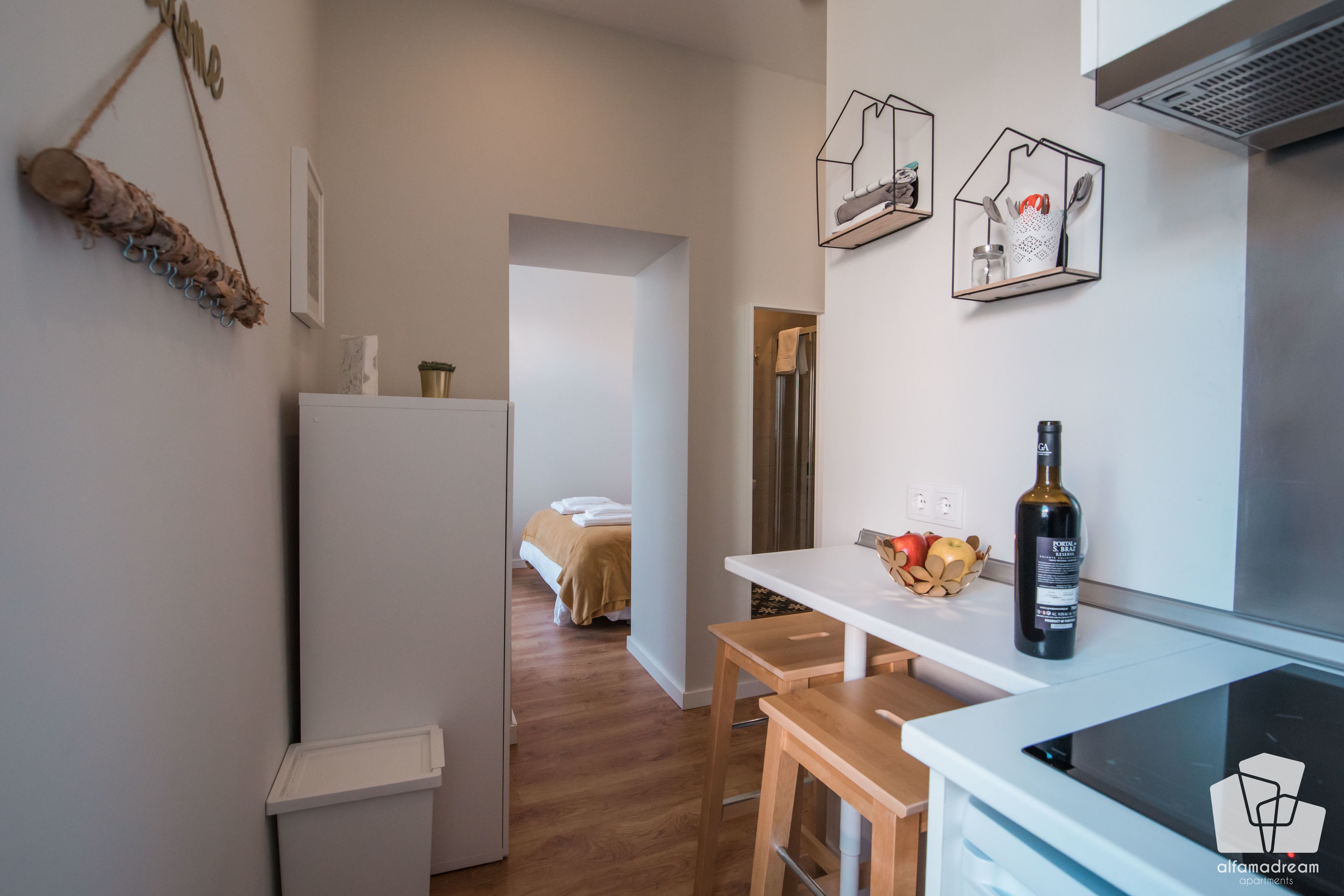 Una cucina compatta con un piano di lavoro bianco, un piccolo angolo ristoro e un frigorifero.