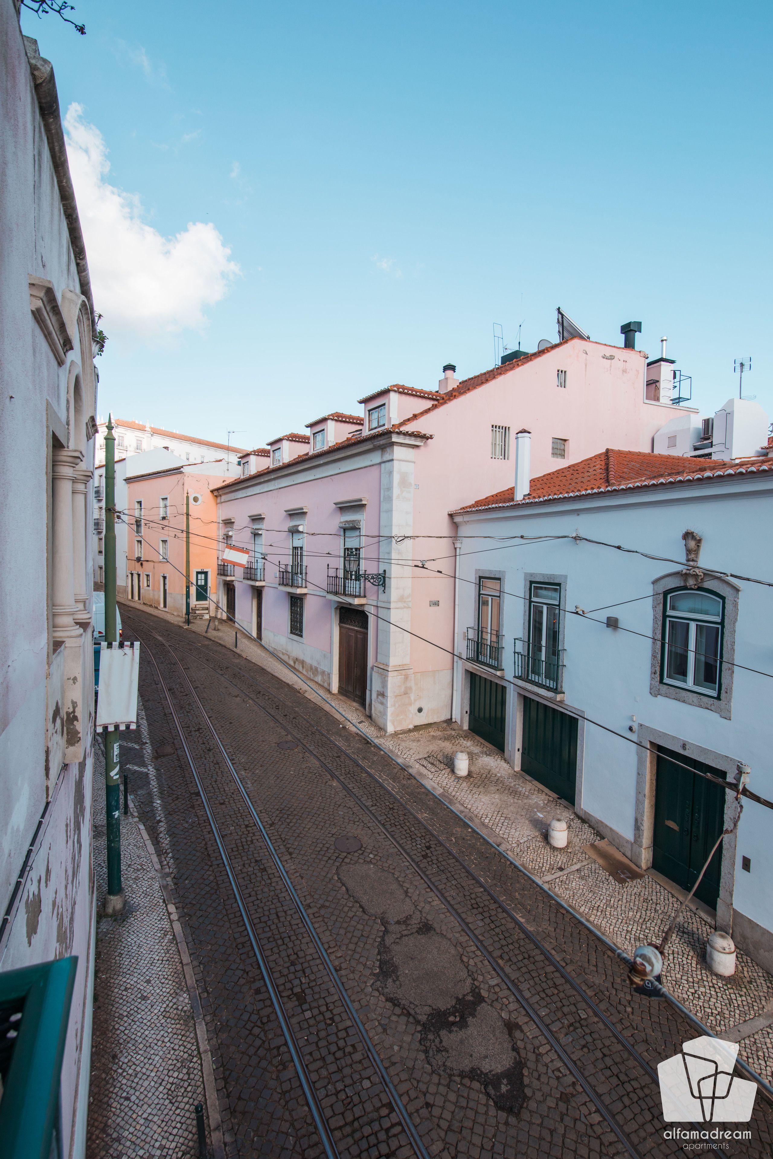 Una strada fiancheggiata da edifici con un binario ferroviario che la attraversa.
