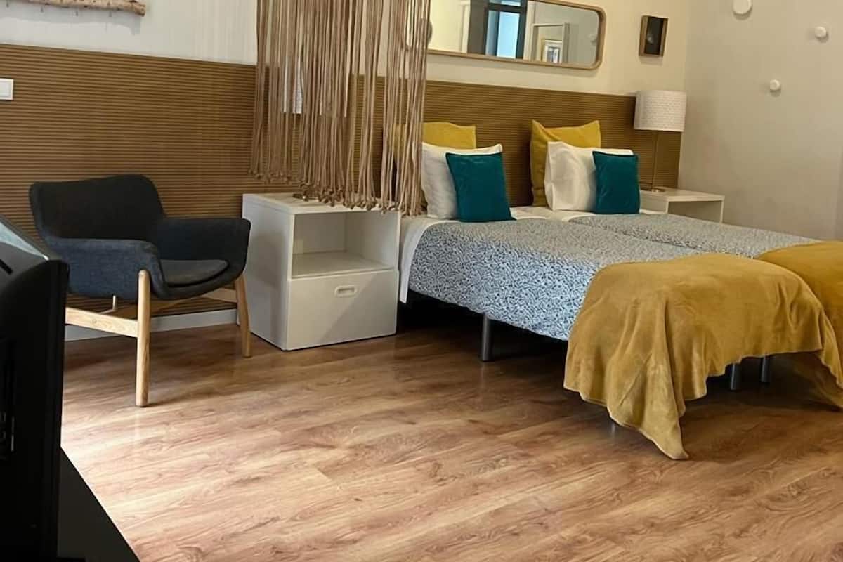 Een moderne slaapkamer met een bed, nachtkastjes, een stoel en een televisie.