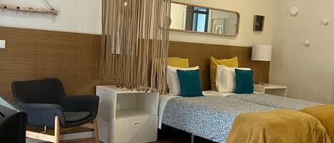 Un dormitorio con cama, mesitas de noche, una silla y una cortina colgante.