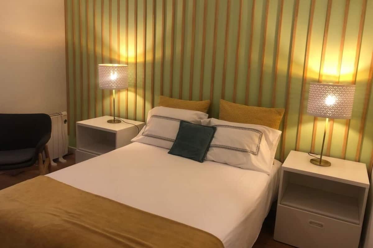 Een hotelkamer met een bed, twee nachtkastjes, een lamp op elk nachtkastje en een stoel.