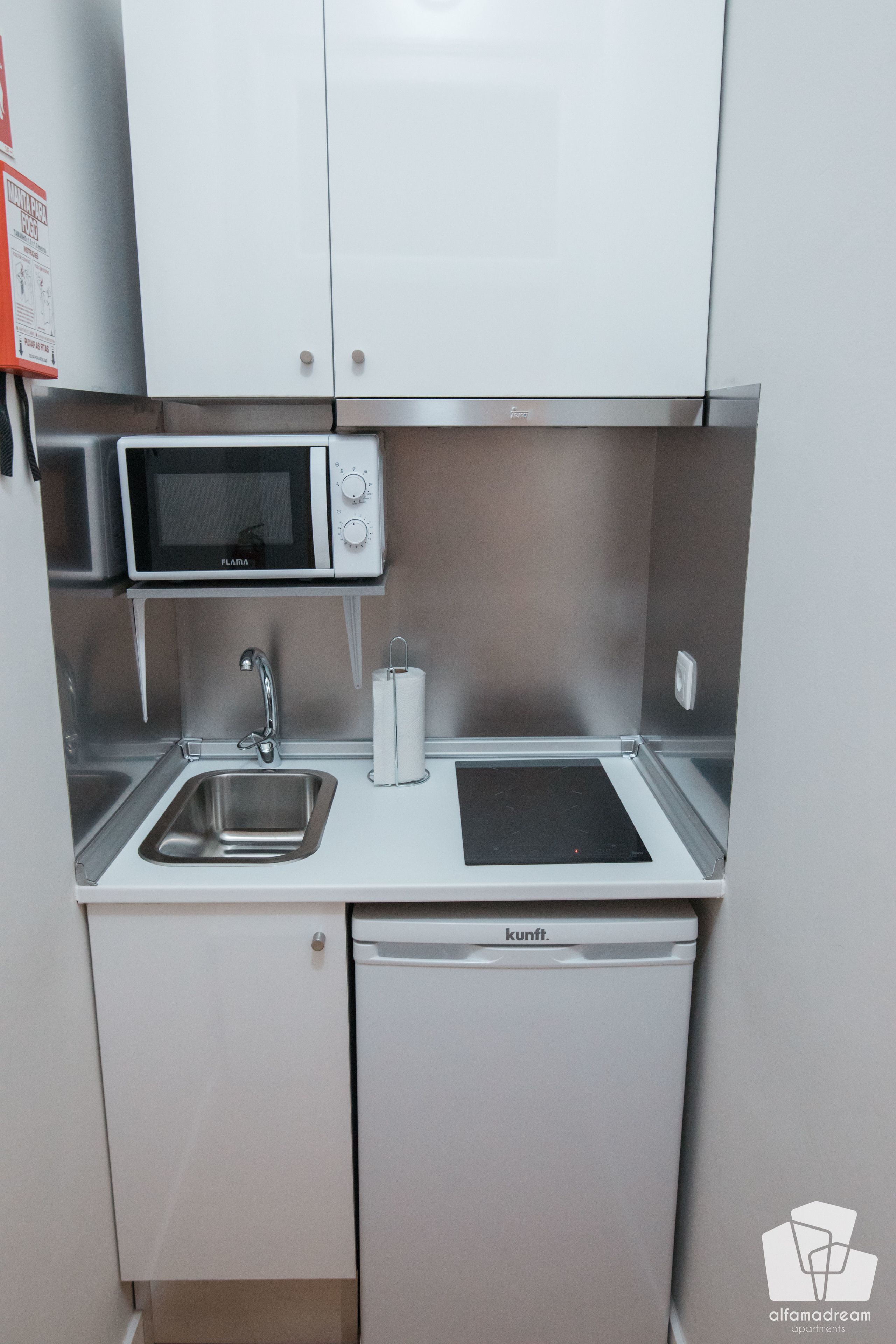 A compact kitchenette with a microwave, sink, and built-in dishwasher.