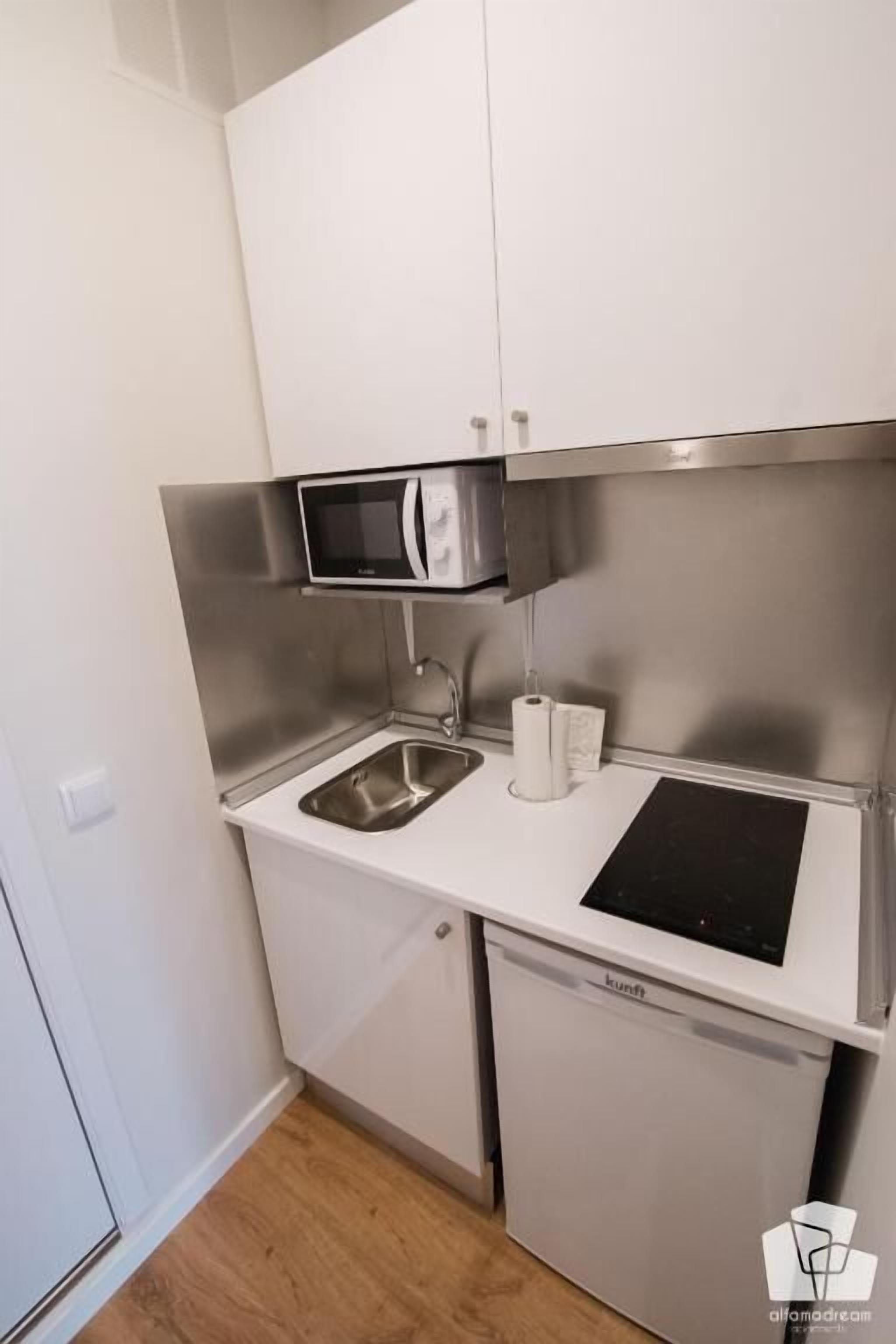 A compact kitchen with a microwave, sink, and built-in dishwasher.