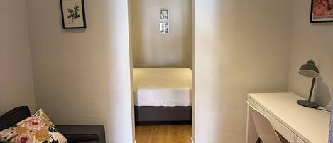 Una habitación pequeña con cama, escritorio y sofá.