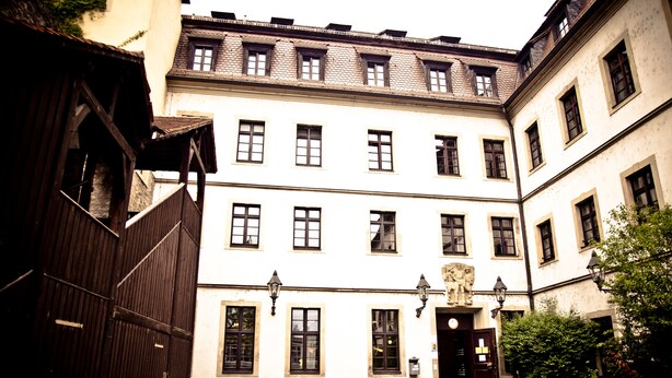 A courtyard with a white building featuring multiple windows and a stone entrance. - Jugendherberge Würzburg - Hostel (Würzburg)