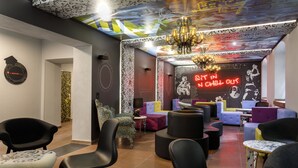 A lounge area with modern furniture, a neon sign, and a patterned ceiling. - Jugendherberge Würzburg - Hostel (Würzburg)