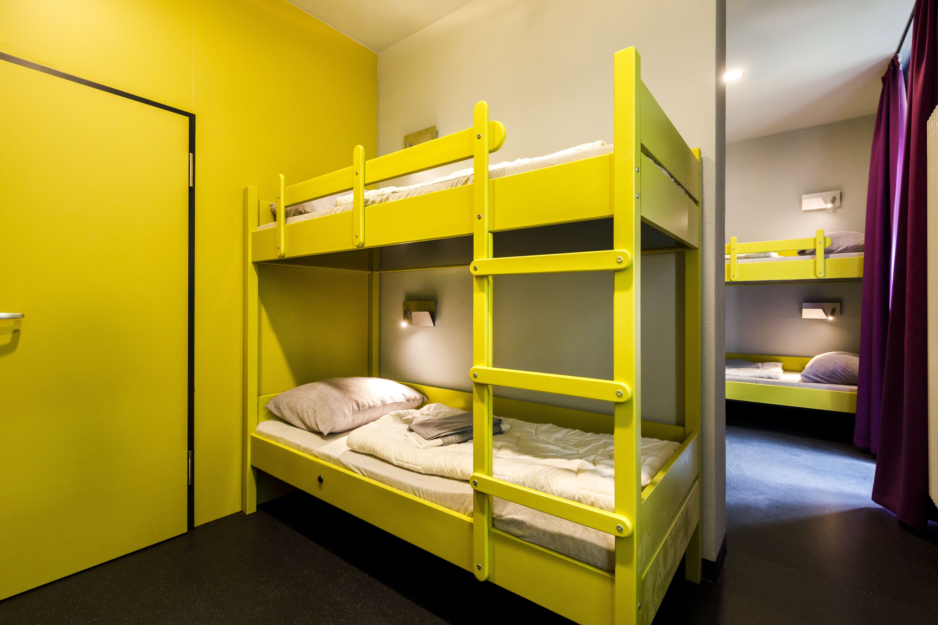 Quarto com beliches, uma porta e um acessório de iluminação.