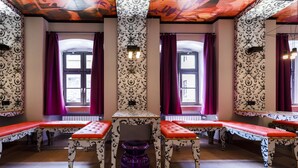 A room with patterned wallpaper, red benches, and a purple vase. - Jugendherberge Würzburg - Hostel (Würzburg)
